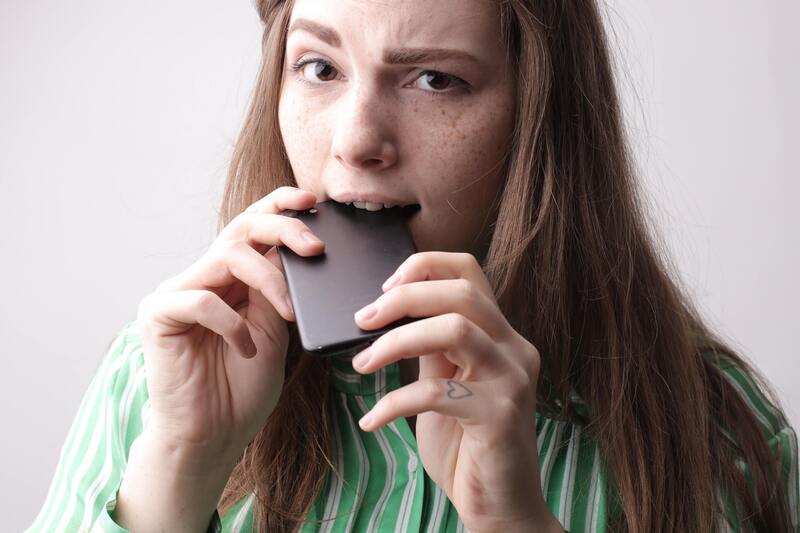 Woman biting a smartphone