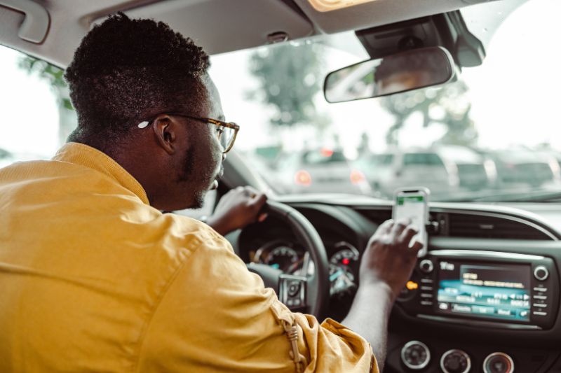 A man driving an uber while checking phone