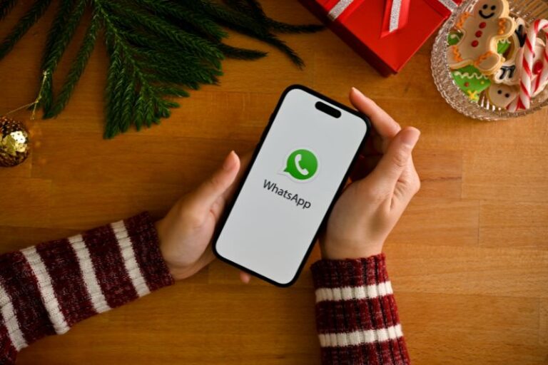 A woman looking at WhatsApp logo on iPhone 14